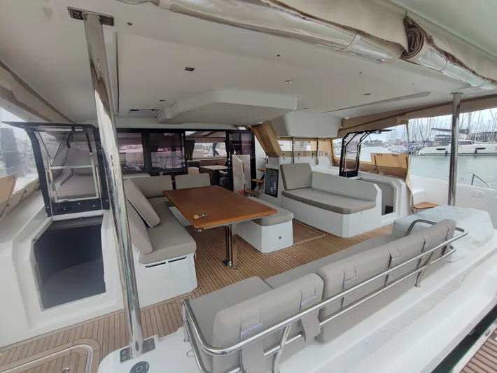  Yacht Photos Pics 2025 Fountaine Pajot Catamaran Aura 51, spacious deck with seating and table, docked at marina.