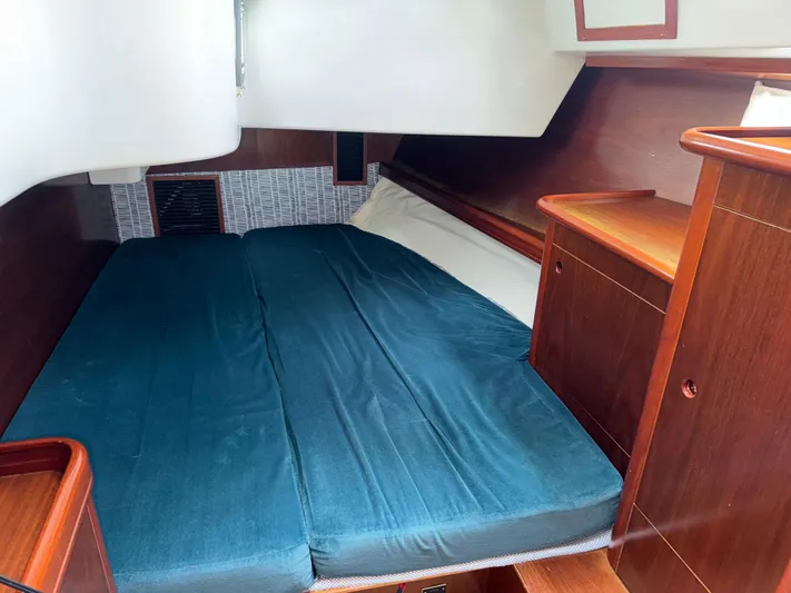 Layla Yacht Photos Pics 1997 Beneteau Oceanis 461 cabin interior with blue bedding and wooden cabinetry.