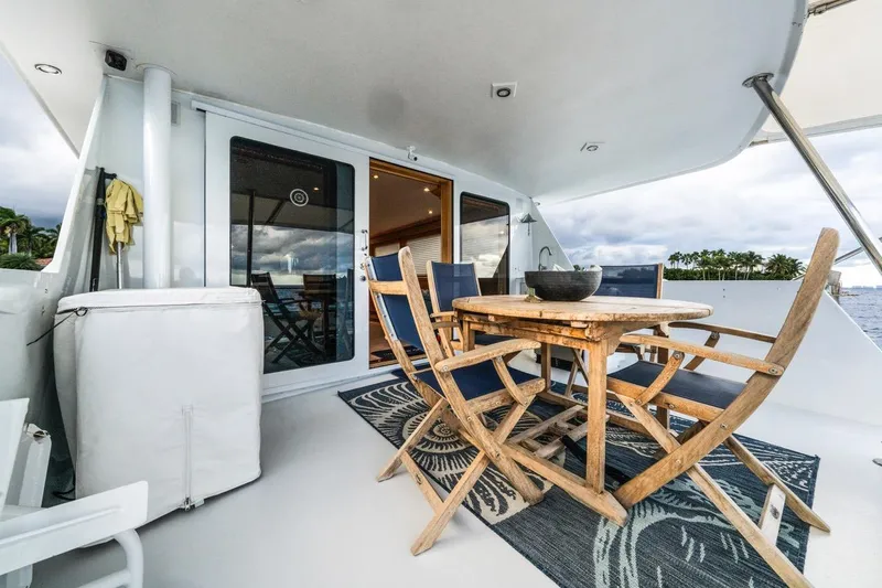  Yacht Photos Pics Outdoor dining area on 2000 Hatteras 74 Cockpit Motor Yacht, featuring wooden table and chairs.