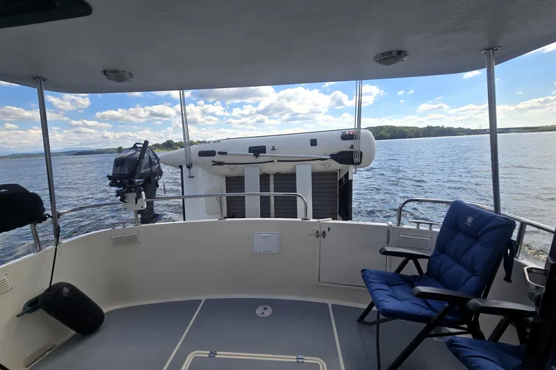 New Bearings Yacht Photos Pics Nordic Tug 42 Flybridge 2000, rear deck view with seating, overlooking serene water and sky.