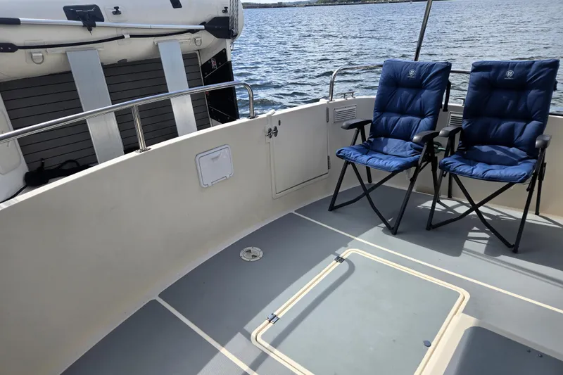 New Bearings Yacht Photos Pics Nordic Tug 42 Flybridge 2000 with blue chairs on deck, overlooking water.