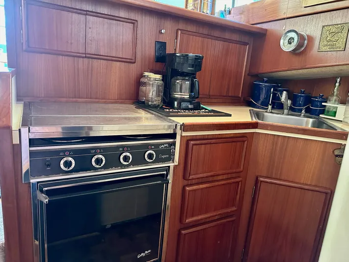 Charisma Yacht Photos Pics 1987 Post 46 SPORT yacht kitchen with stove, coffee maker, and wooden cabinetry.