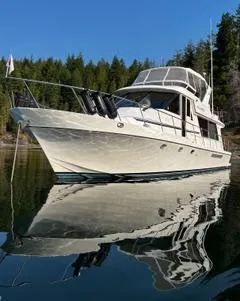  Yacht Photos Pics 2002 Canoe Cove 50 Pilothouse Luxury Yacht on tranquil water, surrounded by trees.