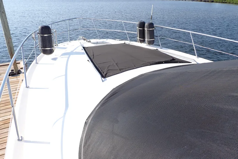 Lattitude Adjustment Yacht Photos Pics 2003 Sea Ray 480 Sedan Bridge yacht deck with black sunshade, docked by calm water.