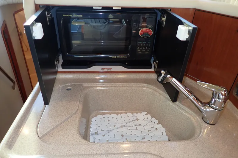 Lattitude Adjustment Yacht Photos Pics 2003 Sea Ray 480 Sedan Bridge kitchen with microwave, sink, and faucet.