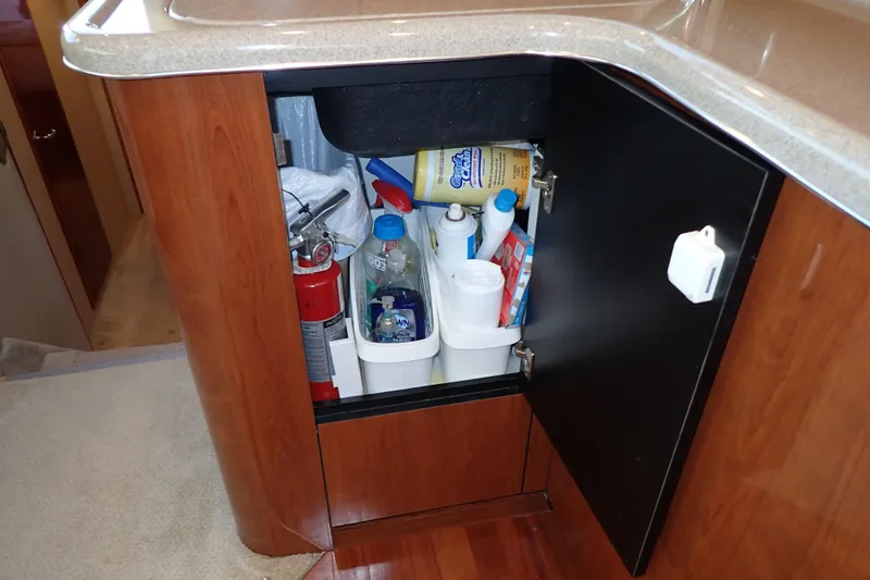 Lattitude Adjustment Yacht Photos Pics Open cabinet in 2003 Sea Ray 480 Sedan Bridge, storing cleaning supplies and fire extinguisher.