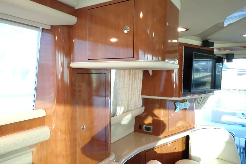 Lattitude Adjustment Yacht Photos Pics Interior of 2003 Sea Ray 480 Sedan Bridge with wood cabinetry and mounted TV.