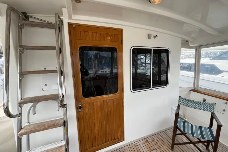 Abina Yacht Photos Pics 2001 Kadey-Krogen 39 yacht deck with wooden door, ladder, and striped chair.