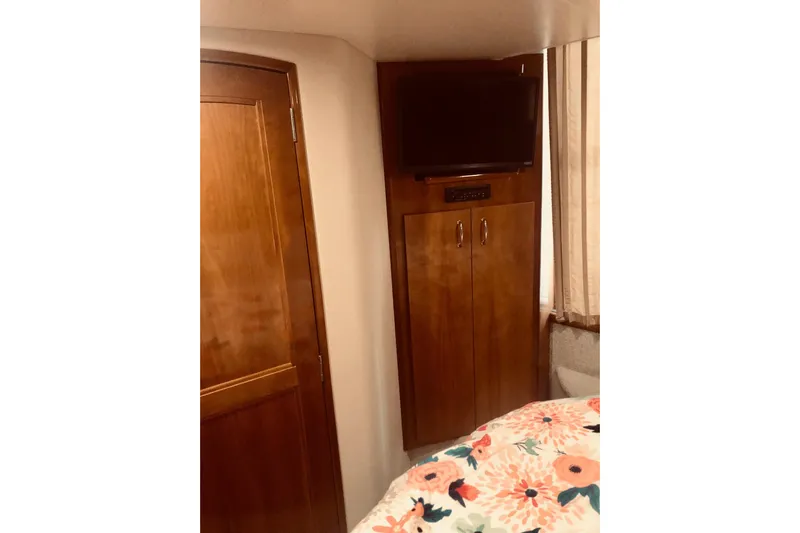 Fire Away Yacht Photos Pics 2005 Carver 444 Cockpit Motor Yacht interior with TV, wooden cabinet, and floral bedding.