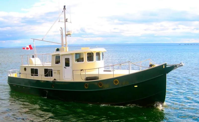  Yacht Photos Pics Custom 2010 trawler boat with Canadian flag on calm waters under a cloudy sky.