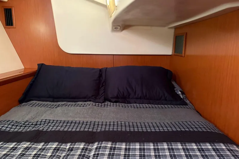  Yacht Photos Pics Cozy cabin bed in 2008 Beneteau 49 sailboat with plaid bedding and wooden paneling.