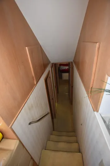 Crazy Train Yacht Photos Pics Stairway inside 1996 Hatteras 50 Convertible yacht, featuring wooden paneling and narrow passage.