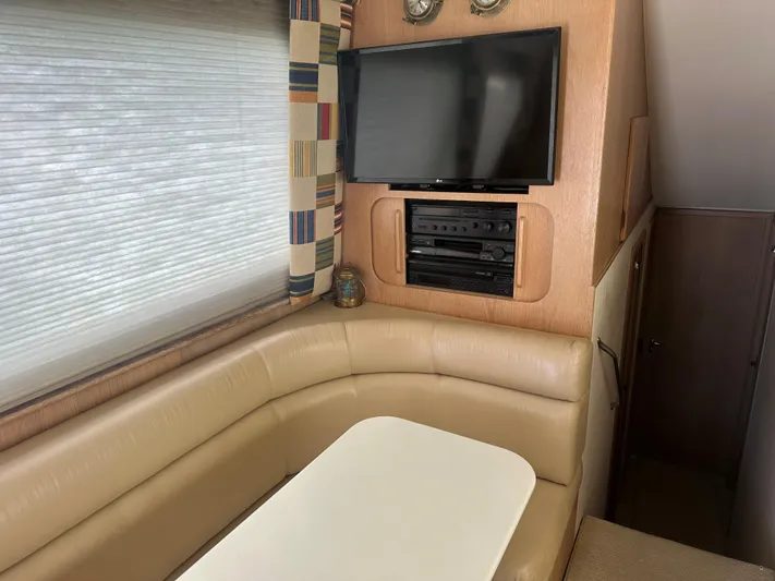 Crazy Train Yacht Photos Pics 1996 Hatteras 50 Convertible interior with beige seating, table, TV, and entertainment system.