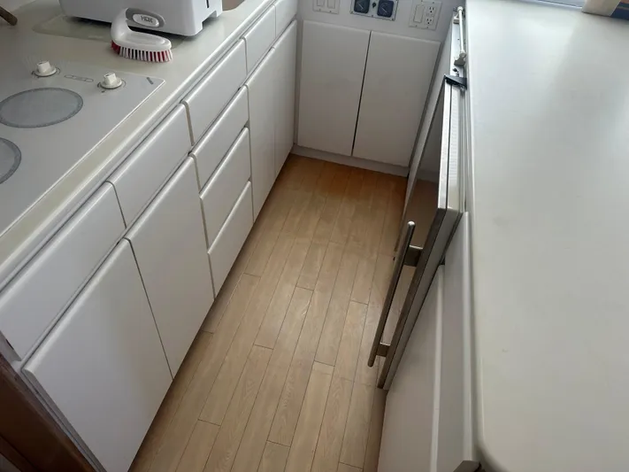 Crazy Train Yacht Photos Pics White kitchen interior on a 1996 Hatteras 50 Convertible yacht, featuring cabinets and appliances.