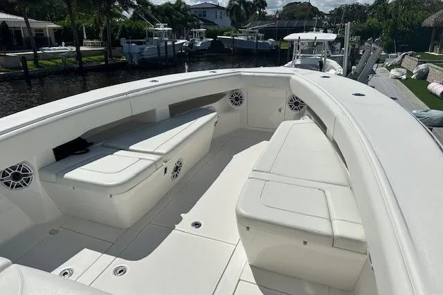 Reel Craft Yacht Photos Pics 2024 SeaVee 340Z boat interior with white seating and speakers, docked near waterfront homes.