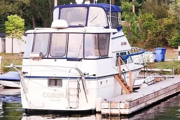  Yacht Photos Pics 1988 Hatteras 43 Motor Yacht docked at a marina, surrounded by greenery.