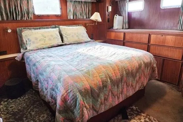  Yacht Photos Pics Cozy bedroom interior of 1988 Hatteras 43 Motor Yacht with colorful bedding and wood paneling.