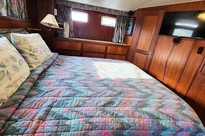  Yacht Photos Pics 1988 Hatteras 43 Motor Yacht bedroom with colorful quilt, wood paneling, and mounted TV.