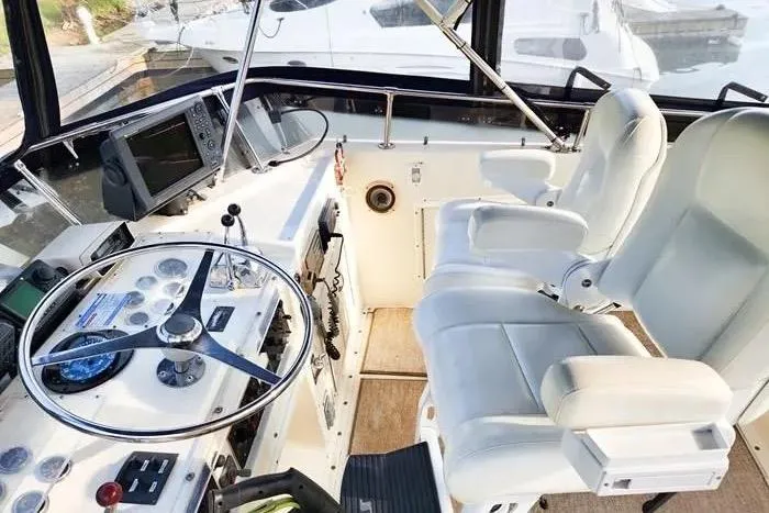  Yacht Photos Pics 1988 Hatteras 43 Motor Yacht helm with steering wheel, navigation equipment, and white captain chairs.