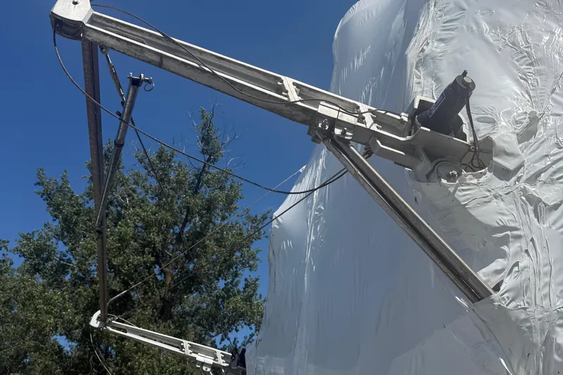  Yacht Photos Pics Crane arm on 1988 Hatteras 43 Motor Yacht against blue sky and trees.