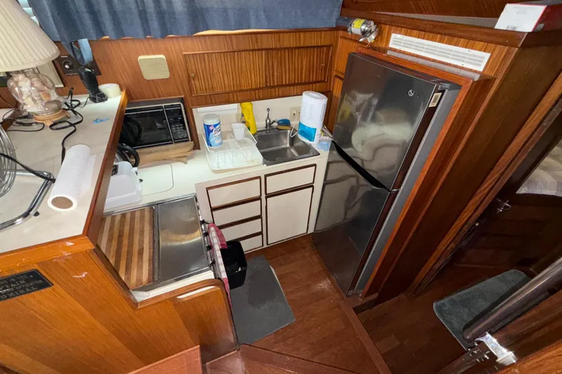  Yacht Photos Pics Compact kitchen area in a 1988 Hatteras 43 Motor Yacht with wooden cabinetry and modern appliances.