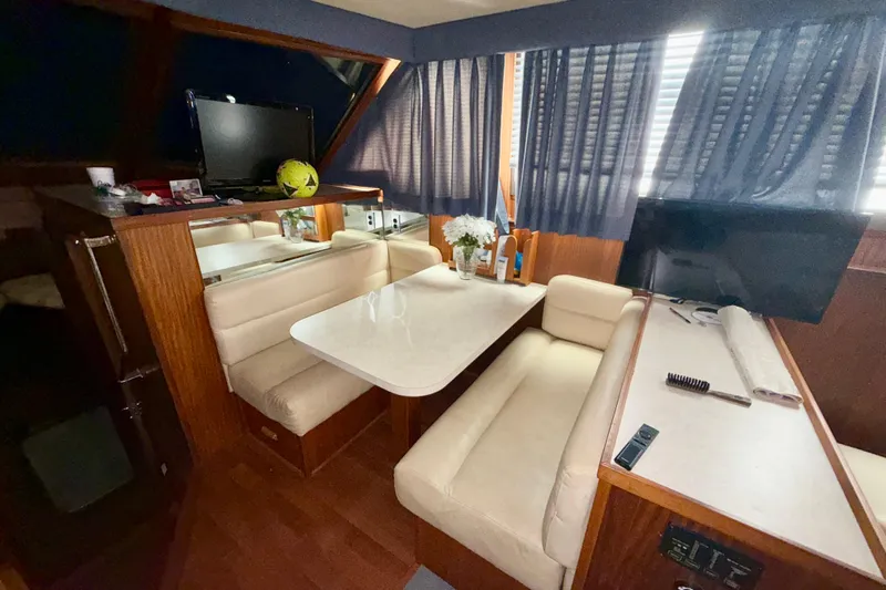  Yacht Photos Pics 1988 Hatteras 43 Motor Yacht interior with dining area, TV, and blue curtains.