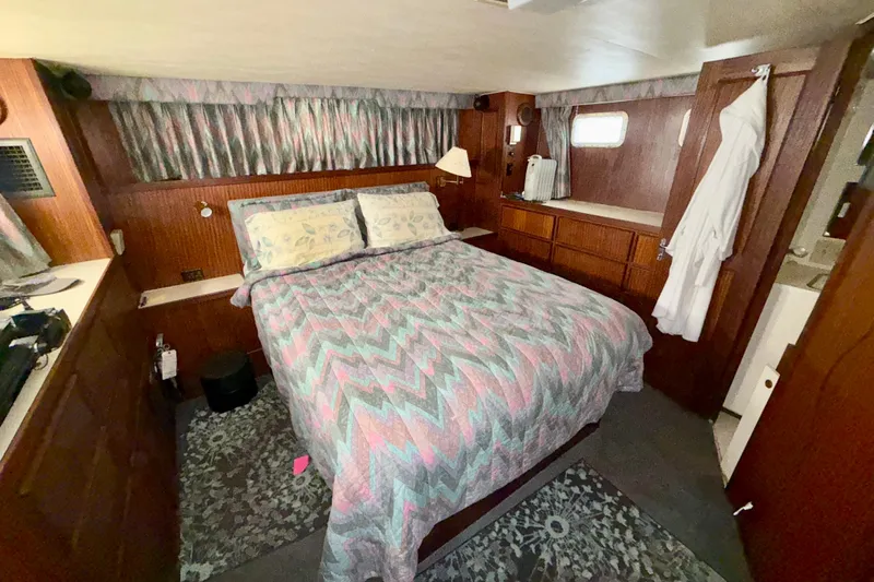  Yacht Photos Pics Cozy bedroom interior of 1988 Hatteras 43 Motor Yacht with patterned bedding and wood paneling.