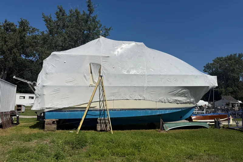  Yacht Photos Pics 1988 Hatteras 43 Motor Yacht covered in white tarp, on land with ladder nearby.