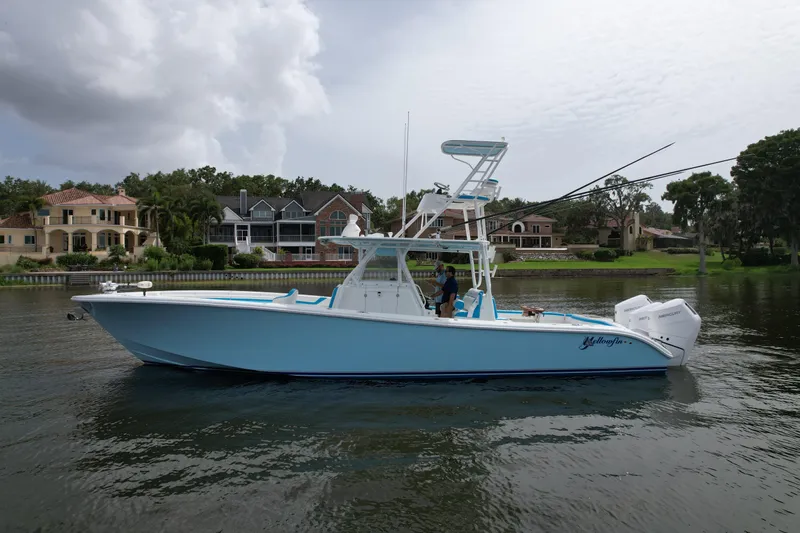 Blue Eyed Yacht Photos Pics 2016 Yellowfin 39 boat on calm water, with luxury homes in the background.