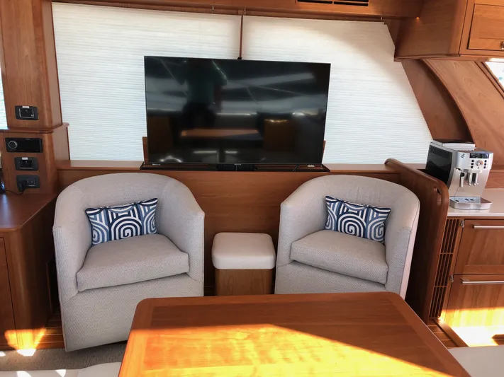 Apricity Yacht Photos Pics Interior of 2021 Sabre 58 Salon Express with TV, chairs, and wooden accents.