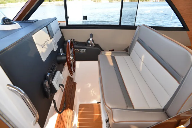 Fluidmotion Yacht Photos Pics 2020 Cutwater C-30S boat interior with Garmin navigation, wooden steering wheel, and cushioned seating.