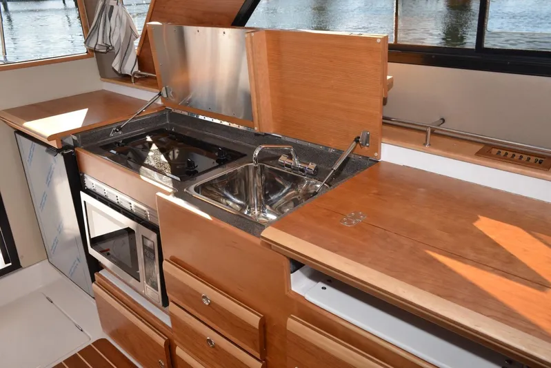 Fluidmotion Yacht Photos Pics 2020 Cutwater C-30S boat kitchen with stove, sink, and microwave, featuring wooden cabinetry.