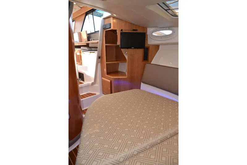 Fluidmotion Yacht Photos Pics 2020 Cutwater C-30S cabin interior with bed, TV, and wooden cabinetry.