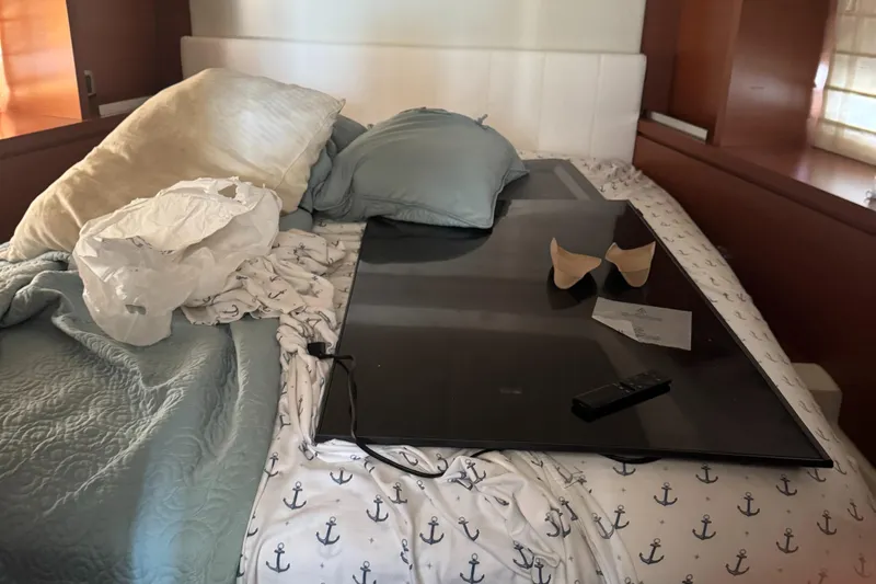  Yacht Photos Pics Messy bed with pillows, TV, and remote in a 2015 Prestige 450 yacht cabin.