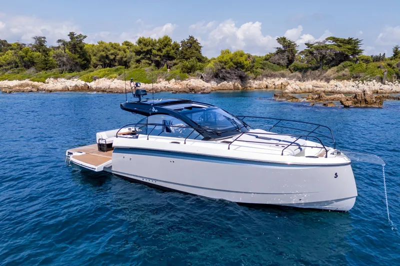  Yacht Photos Pics 2026 Beneteau Gran Turismo 40 yacht cruising near rocky shoreline under clear skies.