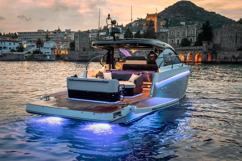  Yacht Photos Pics 2026 Beneteau Gran Turismo 40 yacht illuminated on water at sunset, near historic buildings.