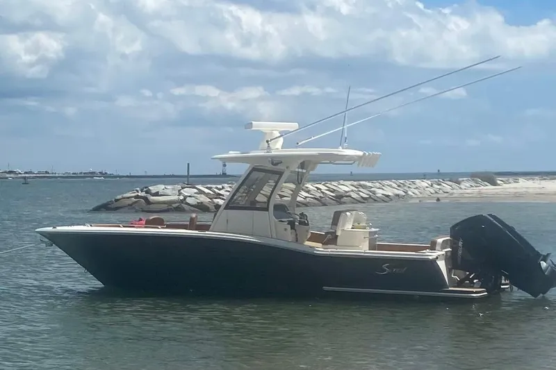  Yacht Photos Pics 2023 Scout 277 LXF boat on calm water near rocky shoreline.
