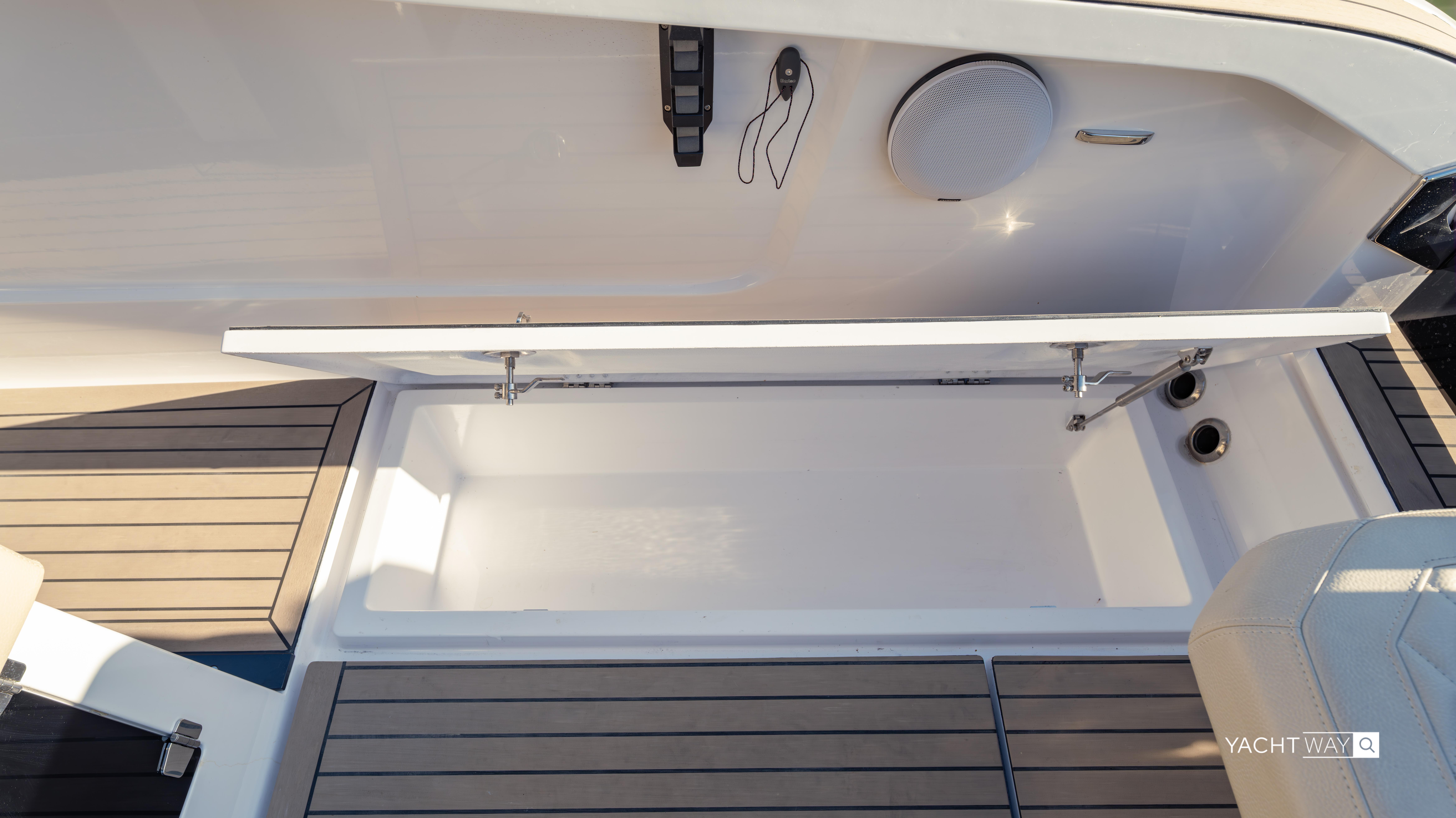 Open storage compartment on 2025 Rand Roamer boat with wooden deck accents.