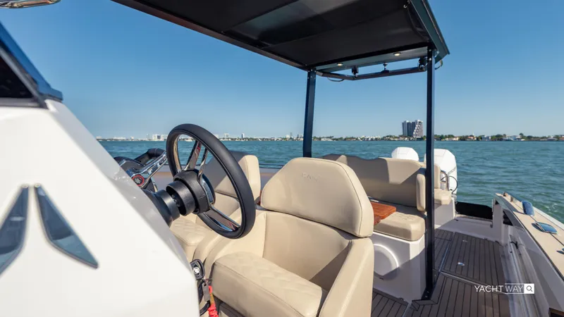  Yacht Photos Pics 2025 Rand Roamer boat interior with steering wheel, beige seating, and open water view.