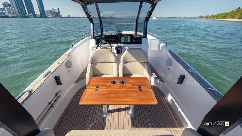  Yacht Photos Pics 2025 Rand Roamer boat interior with wooden table, open water view, and city skyline.
