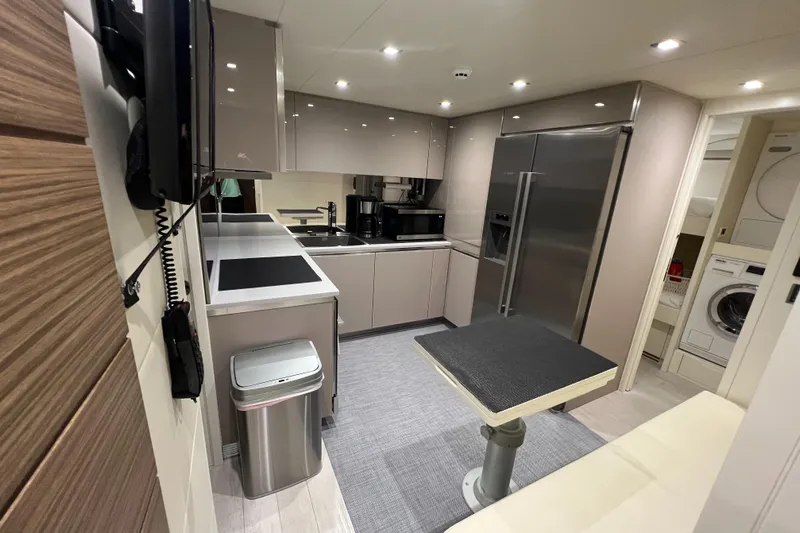 Right Now! Yacht Photos Pics Modern kitchen interior of 2017 Pershing 92 Motor Yacht with sleek appliances and dining area.