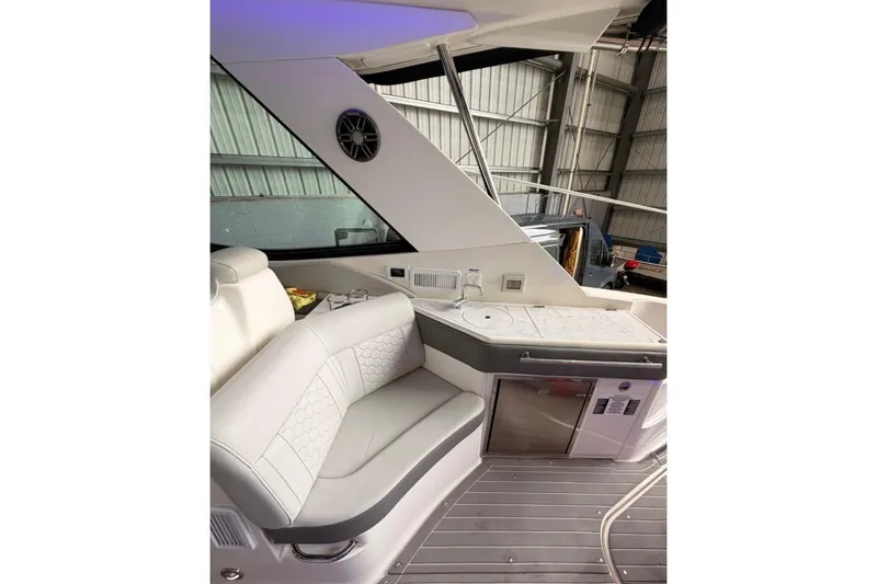  Yacht Photos Pics 2022 Sea Ray Sundancer 320 Outboard interior with seating and kitchenette in a boat garage.