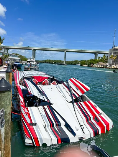 Yacht Photos Pics Colorful 2019 MTI 48 speedboat docked by a scenic waterway under a clear blue sky.