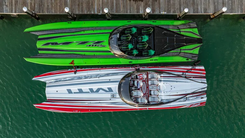  Yacht Photos Pics Two MTI 48 powerboats, green and red, docked side by side, aerial view.