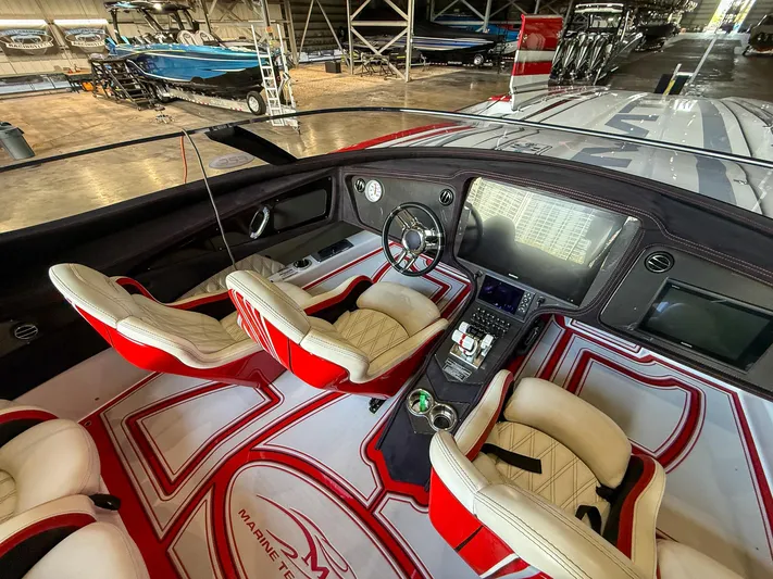  Yacht Photos Pics Interior of a 2019 MTI 48 boat with red and white seating and advanced dashboard.