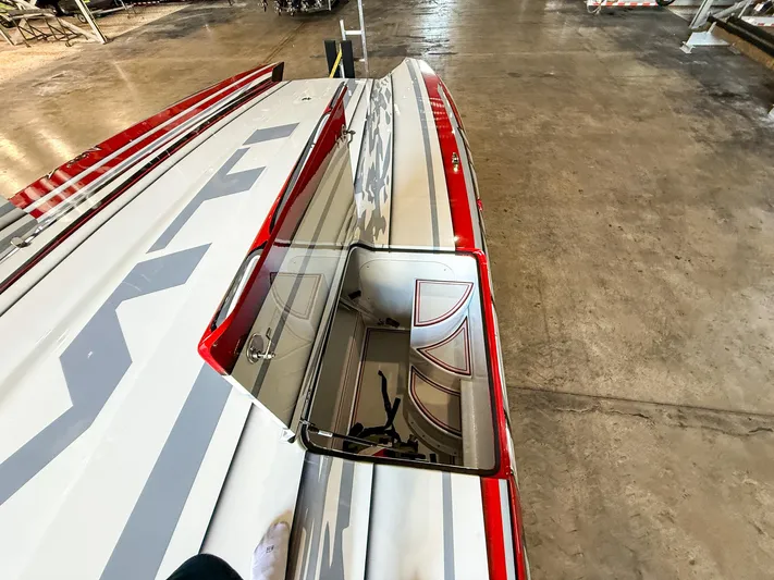  Yacht Photos Pics 2019 MTI 48 boat with red and gray design, open hatch, in a garage.