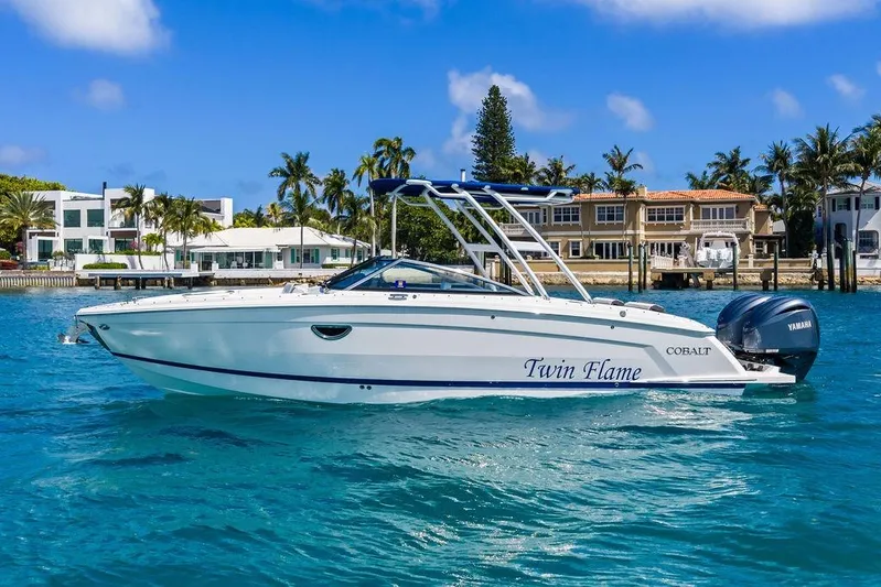 Twin Flame Yacht Photos Pics 2022 Cobalt R8 Outboard boat on clear blue water near luxury waterfront homes.