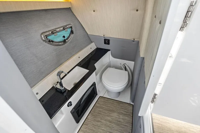 Twin Flame Yacht Photos Pics 2022 Cobalt R8 Outboard boat bathroom with sink, toilet, and porthole window.