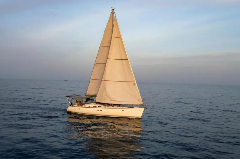  Yacht Photos Pics 2002 Beneteau Oceanis Clipper 473 sailing on calm ocean waters at sunset.