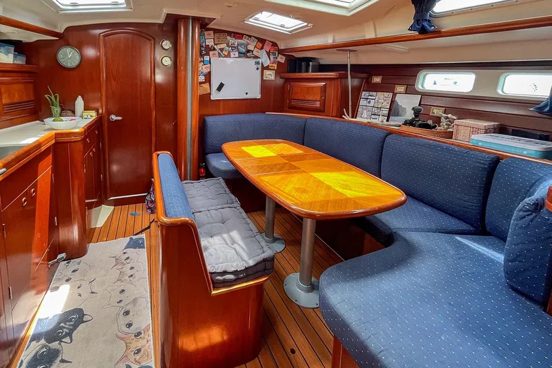  Yacht Photos Pics Interior of 2002 Beneteau Oceanis Clipper 473 yacht with wooden dining area and blue seating.